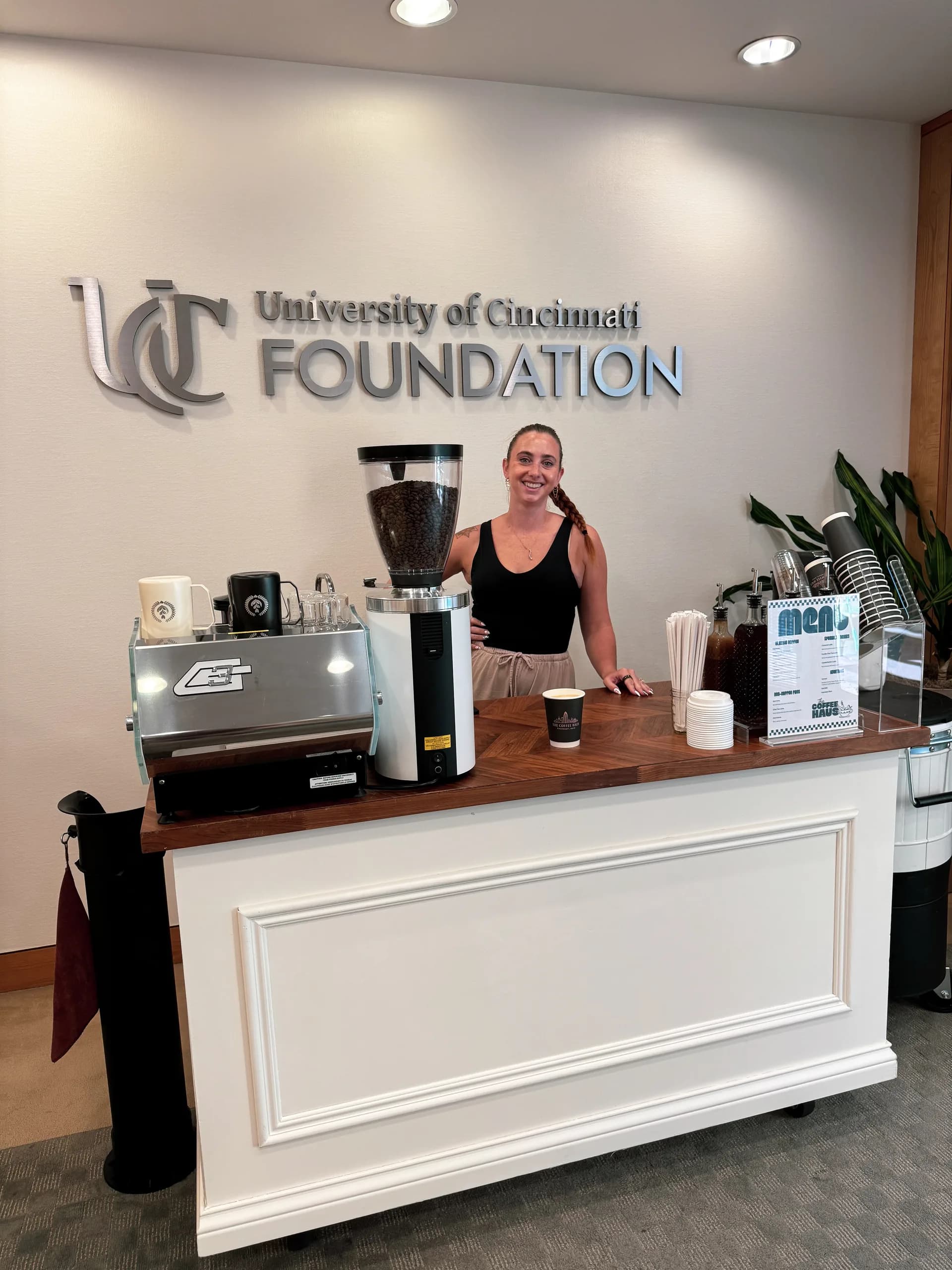 The Coffee Haus mobile coffee cart set up at the University of Cincinnati Foundation with a barista serving guests